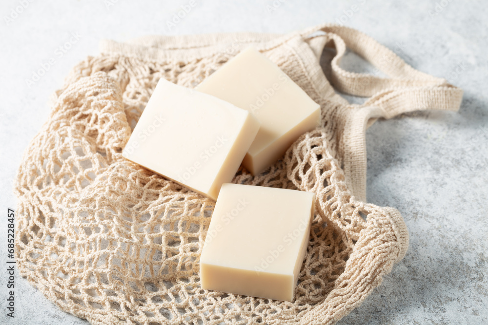 Natural handicraft soap bars beige color on mesh bag background close-up Natural handicraft soap bars beige color on mesh bag background close-up