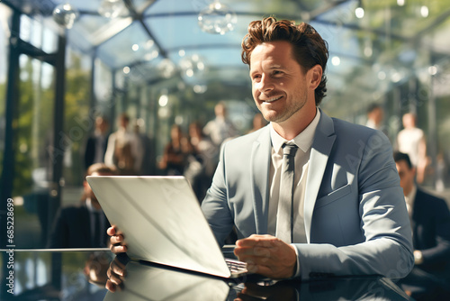 Young businessman in suit and tie holding a laptop in front of people.