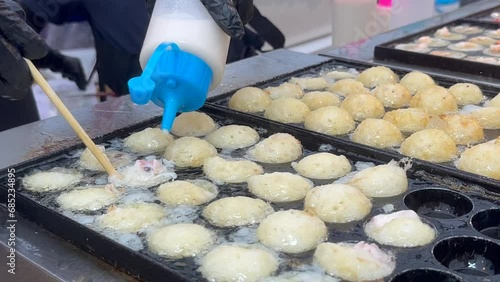 rocess to Cooking Takoyaki on hot pan Japan street food. Making takoyaki filled with octopus pieces on a hot pan in the street food f photo