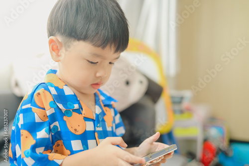 Asian boy using a smartphone. Kid playing with mobile phone.Children's screen addiction