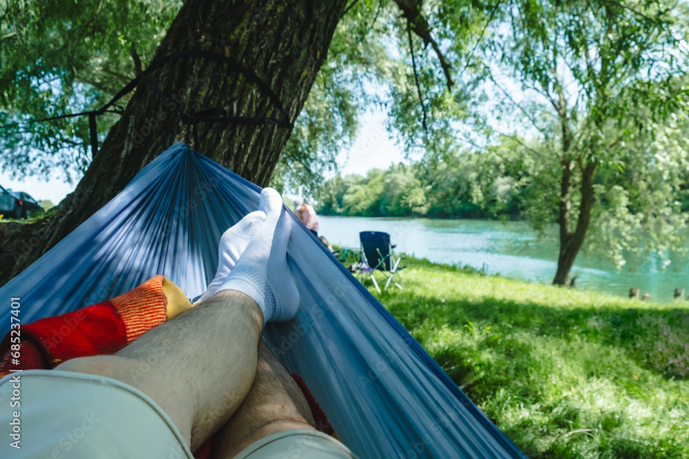 pov man laying down on hammock resting at riverside