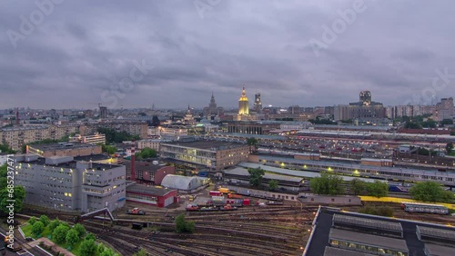 Evening top view of three railway stations day to night transition timelapse at the Komsomolskaya square in Moscow, Russia. Aerial panorama view from rooftop. Trains on tracks. Stalin skyscrapers photo