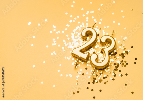 23 years birthday celebration festive background made with golden candle in the form of number Twenty three lying on sparkles. Universal holiday banner with copy space. photo