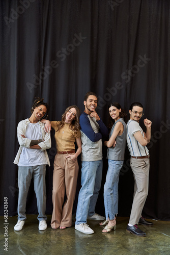 full length of creative multiethnic team posing on black backdrop in modern office, group photo
