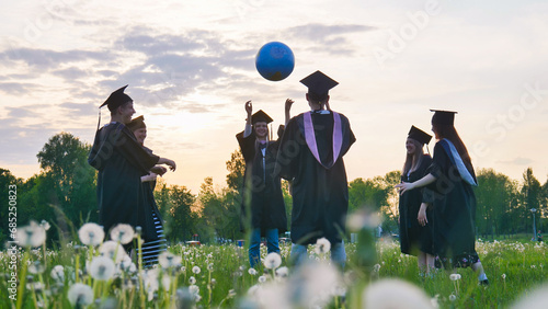 Graduates in costume playing with a ball at sunset. photo