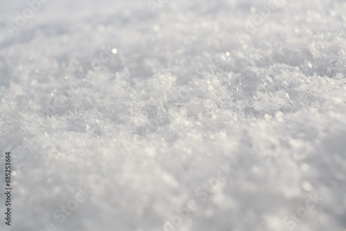 Winter background of snowy surface with melted snowflakes. Natural snow texture. Pattern of snow surface. Horizontal format.