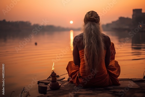 religious hindu elderly man sitting on a rock in the river meditating and praying