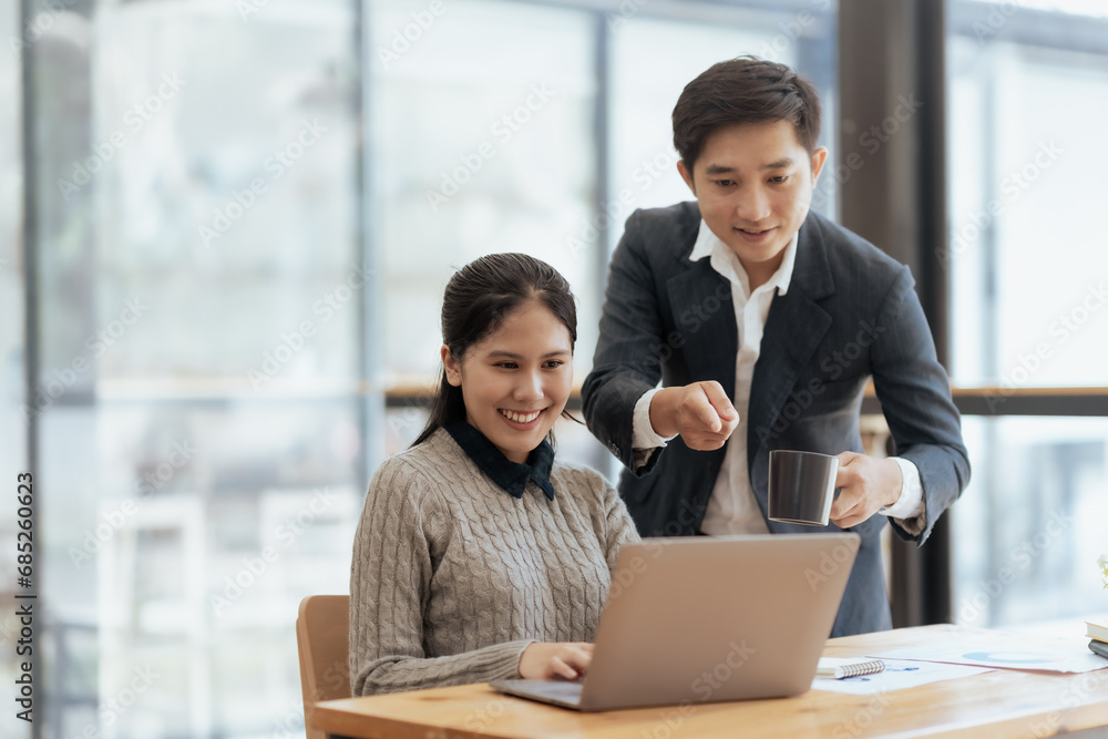Asian businesswoman and businessman using laptop to discuss and consultation together at meeting. Collaboration of two Asian employees. Two people working in modern office. Asian businesswoman and businessman using laptop to discuss and consultation together at meeting. Collaboration of two Asian employees. Two people working in modern office.