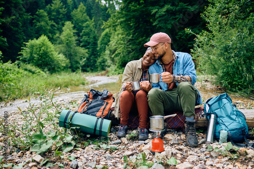 Young couple of hikers enjoying in warm tea while relaxing in nature. photo