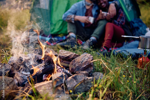 Burning campfire in nature with couple in background.
