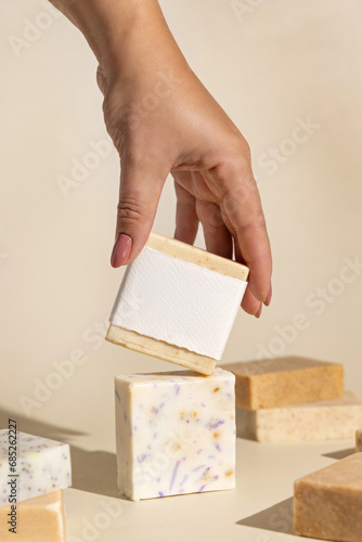 Tableau sur toile Hand keeps natural beige soap bars with blank label on light beige, hard shadows