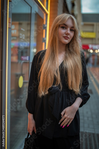 Portrait of a young beautiful blonde girl in dark clothes in an urban environment.
