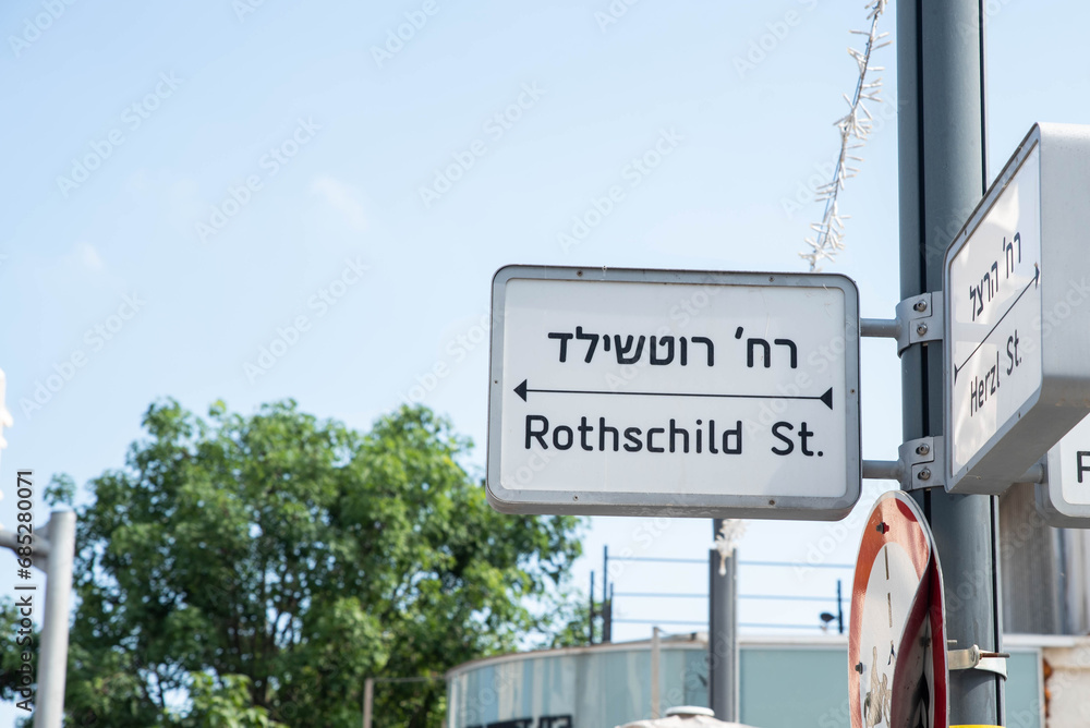 Urban city navigation street name sign, crossroad corner Rothschild and Herzl in Rishon Lezion, Israel
