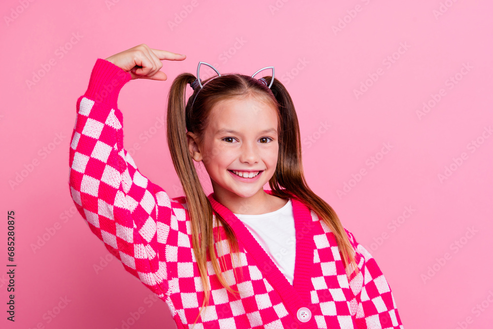 Portrait of good mood schoolgirl with ponytails wear print sweater directing at cat ears on head isolated on pink color background Portrait of good mood schoolgirl with ponytails wear print sweater directing at cat ears on head isolated on pink color background