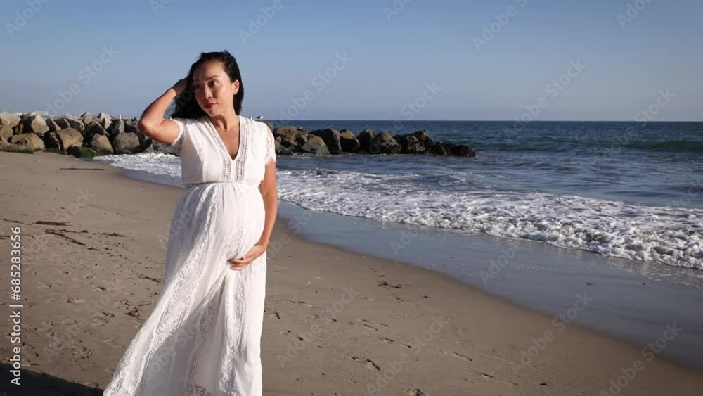 Attractive pregnant Asian woman enjoys a walk on the beach. Attractive pregnant Asian woman enjoys a walk on the beach.