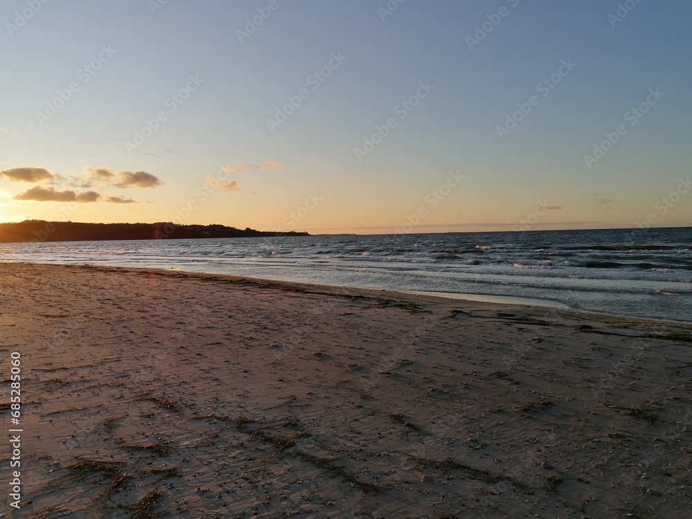 Sandy beach, wavy sea and sky with white clouds