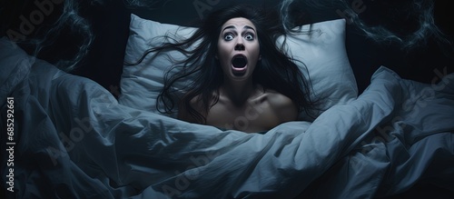 Startled woman arising from a bad dream in her nighttime slumber copy space image photo