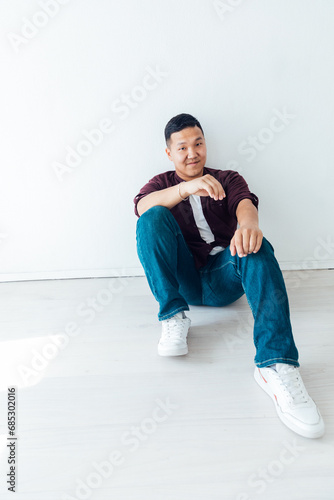 A man sits on the floor on a white background in a studio © dmitriisimakov