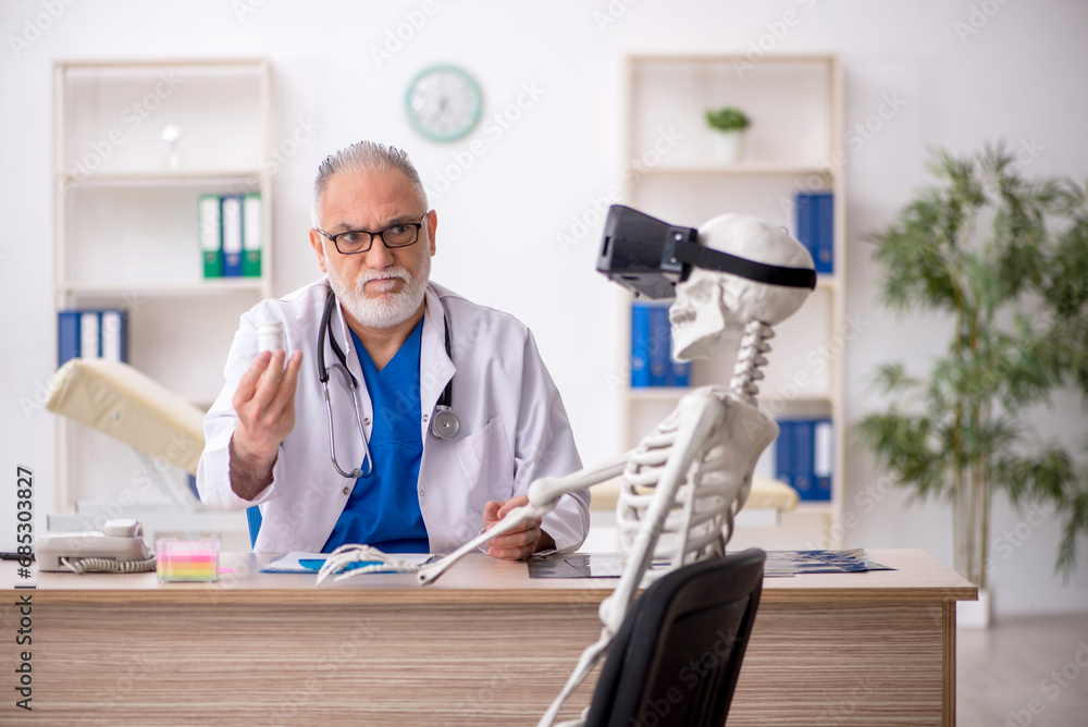 Old male doctor examining skeleton in the clinic Old male doctor examining skeleton in the clinic