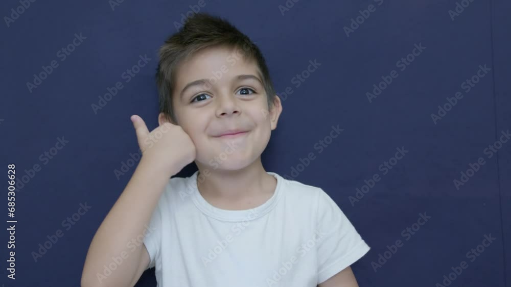 Cute little boy shows thumb up gesture, happy facial expression emotion, slow motion isolated on blue background. High quality 4k footage Cute little boy shows thumb up gesture, happy facial expression emotion, slow motion isolated on blue background. High quality 4k footage