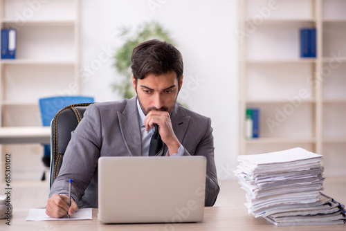 Young male employee and too much work in the office