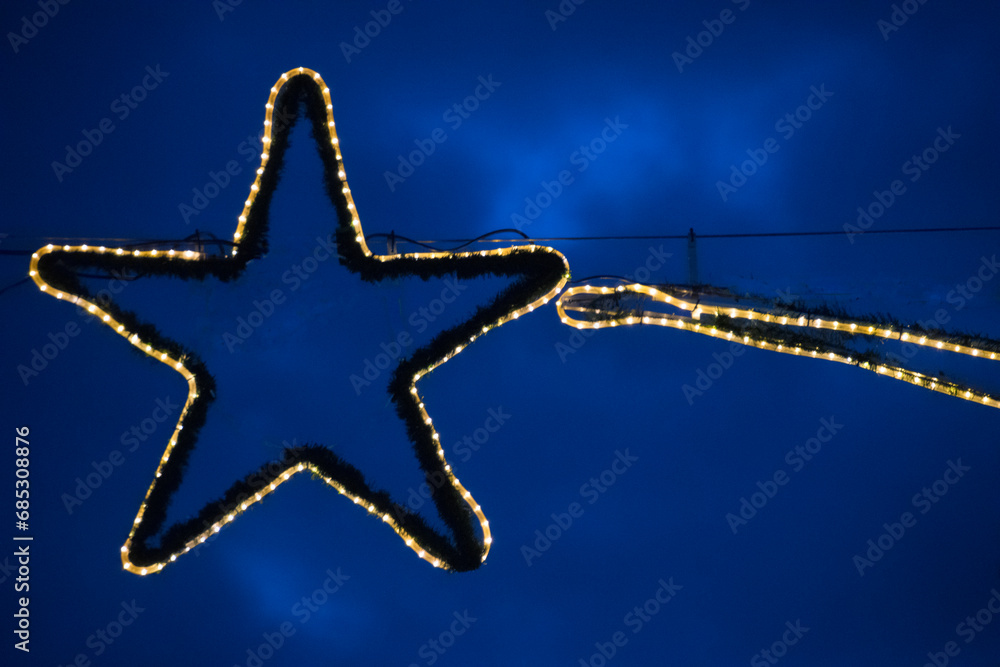 Fototapeta premium Weihnachtsbeleuchtung mit Sternmotiv vor Abendhimmel