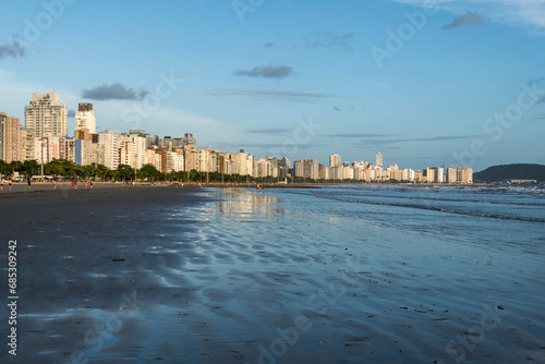 Santos city, Brazil. Late afternoon at Santos beach with waterfront buildings illuminated by sunlight in the blue sky. photo