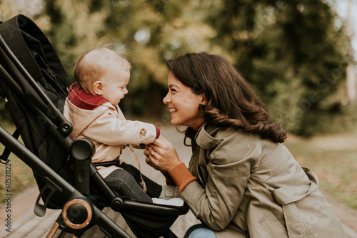 Fotografía Young woman with cute baby girl in baby stroller at the autumn park