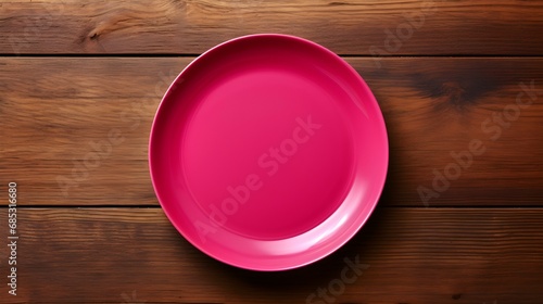 Top View of an empty Plate in hot pink Colors on a wooden Table. Elegant Template with Copy Space