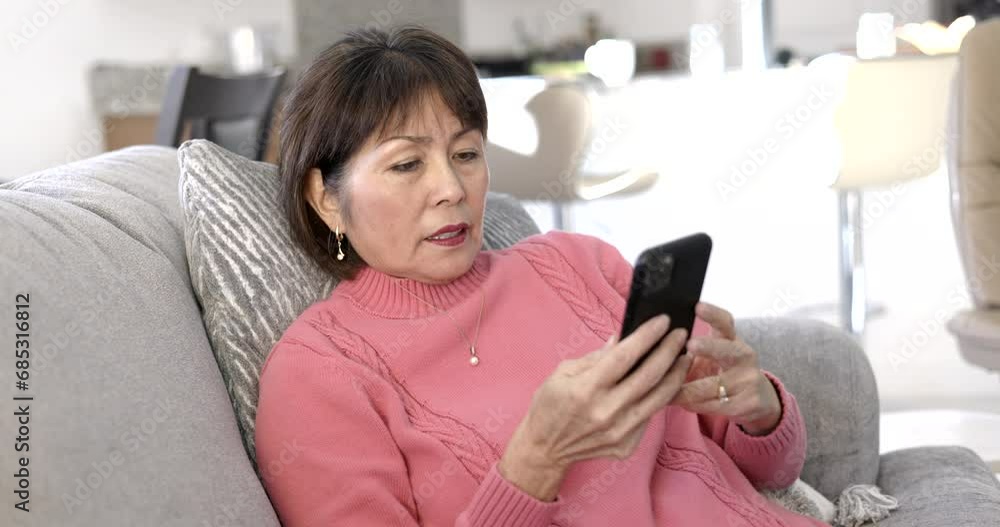 Attractive mature woman relaxing enjoying texting on mobile phone sitting on comfortable sofa Attractive mature woman relaxing enjoying texting on mobile phone sitting on comfortable sofa