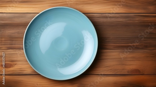 Top View of an empty Plate in light blue Colors on a wooden Table. Elegant Template with Copy Space
