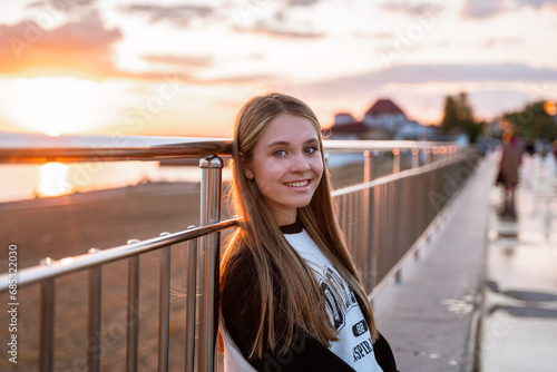 A beautiful teenage girl walks along the city embankment at sunset. Togliatti, Russia - 10 Sep 2023