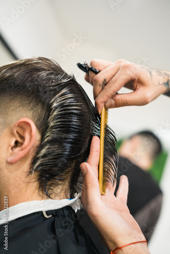barber's hand with comb and scissors cutting the hair