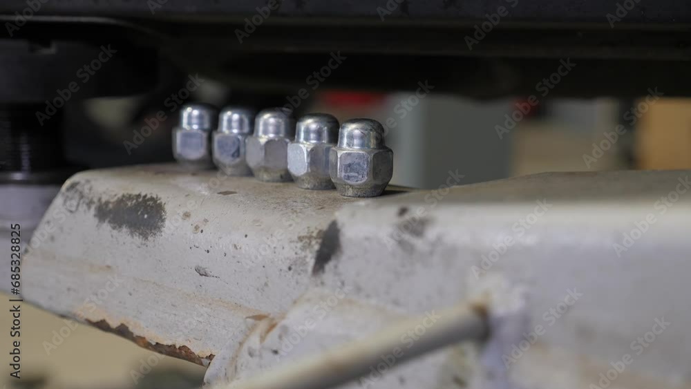 There are a lot of unscrewed nuts from the wheel in the car service. Close-up of the nuts from the unscrewed wheel in the car service. A raised car in the process of repair. There are a lot of unscrewed nuts from the wheel in the car service. Close-up of the nuts from the unscrewed wheel in the car service. A raised car in the process of repair.