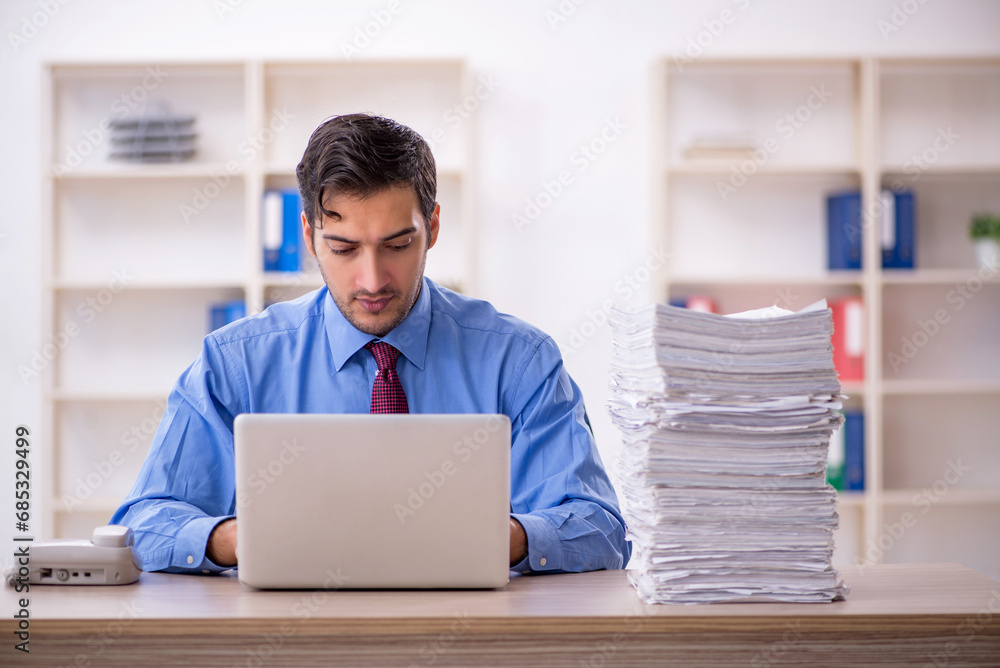 Young male employee and too much work in the office Young male employee and too much work in the office