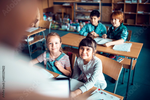 Elementary school kids listening to teacher in classroom photo