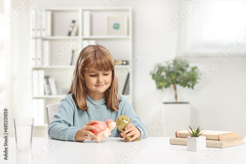 Cute little girl sitting at home and playing with toys