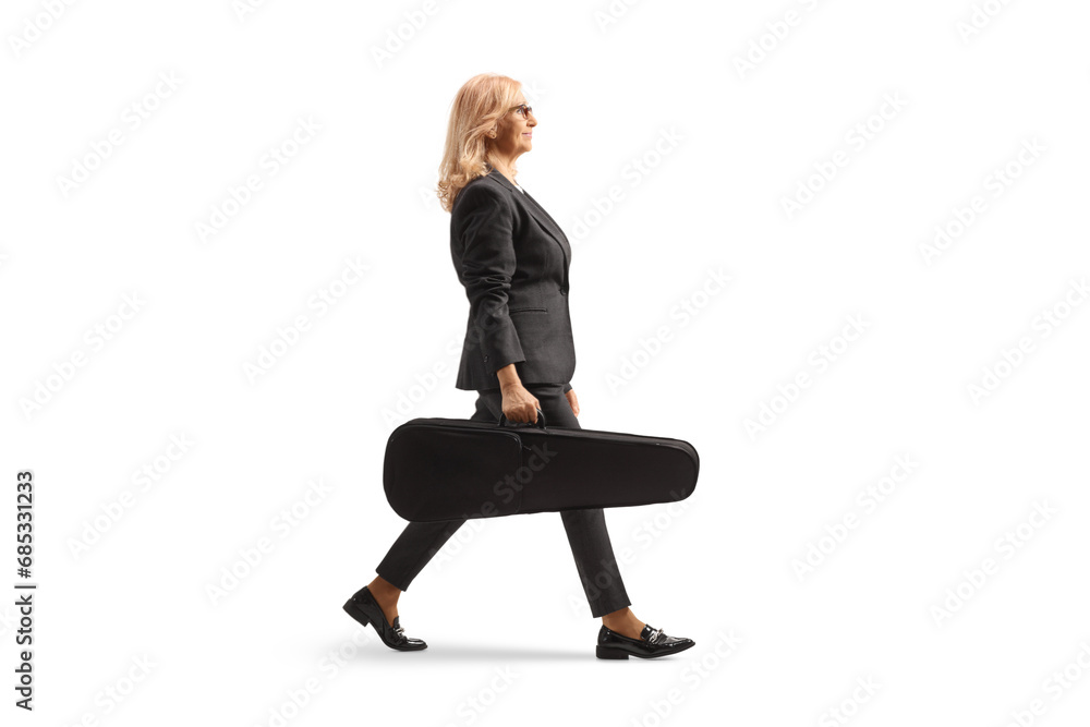Full length profile shot of a woman walking and carrying a violin in a case Full length profile shot of a woman walking and carrying a violin in a case