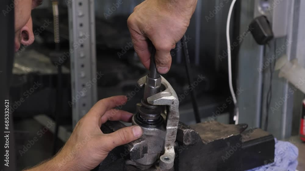 Close-up of the mechanic, we fasten the nut to the part from the machine on the vise. Repair of small parts from a car at a modern service station. Close-up of the mechanic, we fasten the nut to the part from the machine on the vise. Repair of small parts from a car at a modern service station.