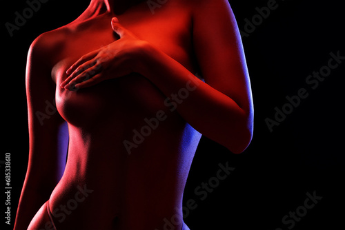 Slim sexy woman in lingerie on a dark background. Her body is illuminated with blue and red lights.