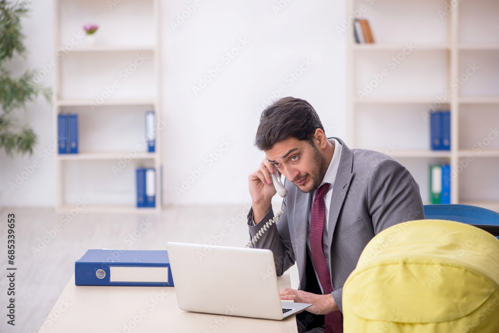 Naklejka premium Young male employee looking after newborn at workplace