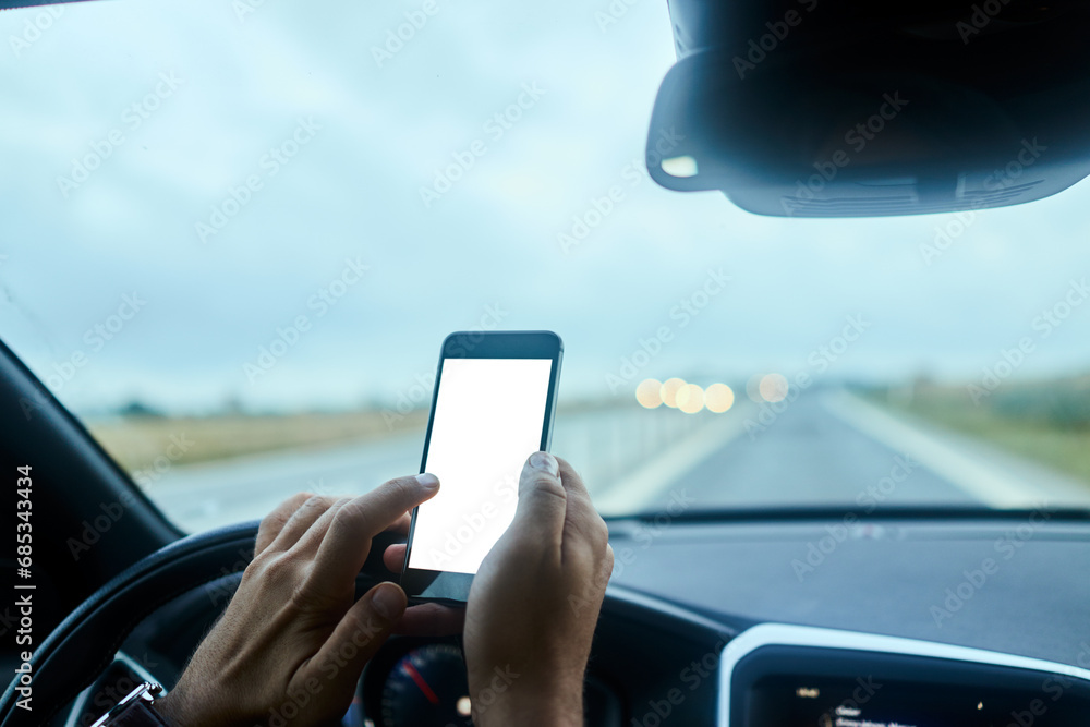 Close up man hands using smartphone at wheel during drive on freeway