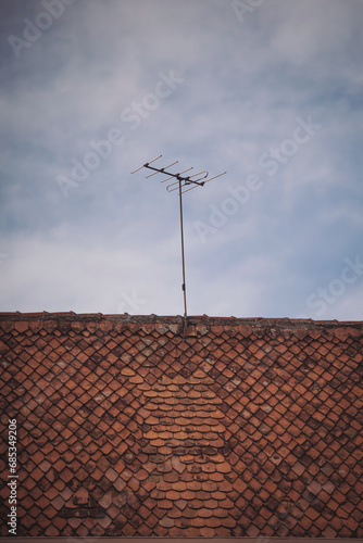 old roof with tiles and antenna. House roof, tile, brown, bricks, old TV antenna.  WIFI Hot Spot Tower on Street. Broadcast television antenna. Old technology communication. © Cristina