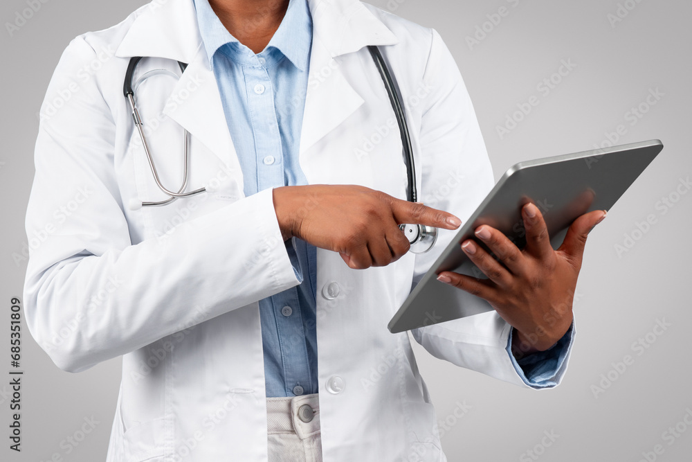 Millennial black woman doctor therapist in white coat, chatting at tablet, typing on gadget Millennial black woman doctor therapist in white coat, chatting at tablet, typing on gadget
