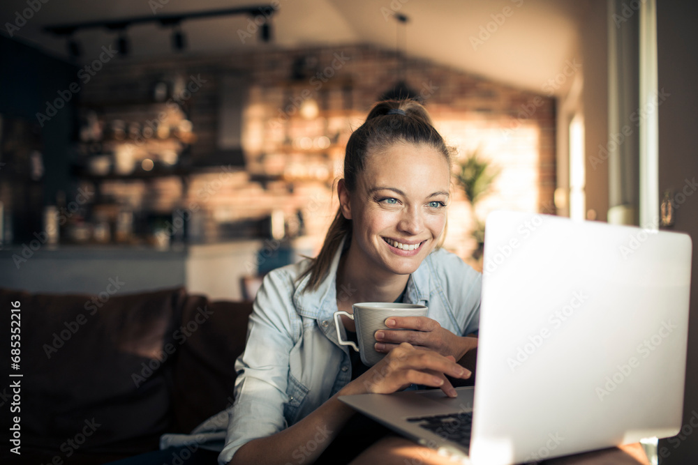 Happy Woman Enjoying Coffee While Working on Laptop at Home Happy Woman Enjoying Coffee While Working on Laptop at Home