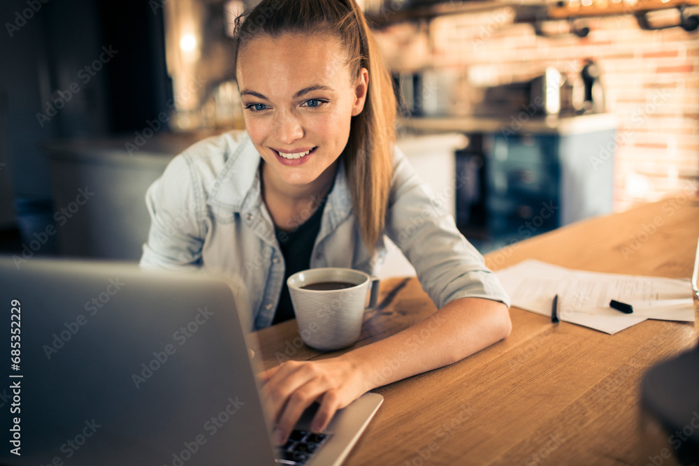 Happy Woman Enjoying Coffee While Working on Laptop at Home Happy Woman Enjoying Coffee While Working on Laptop at Home