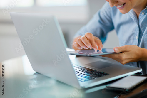 Woman using the smartphone at the laptop
