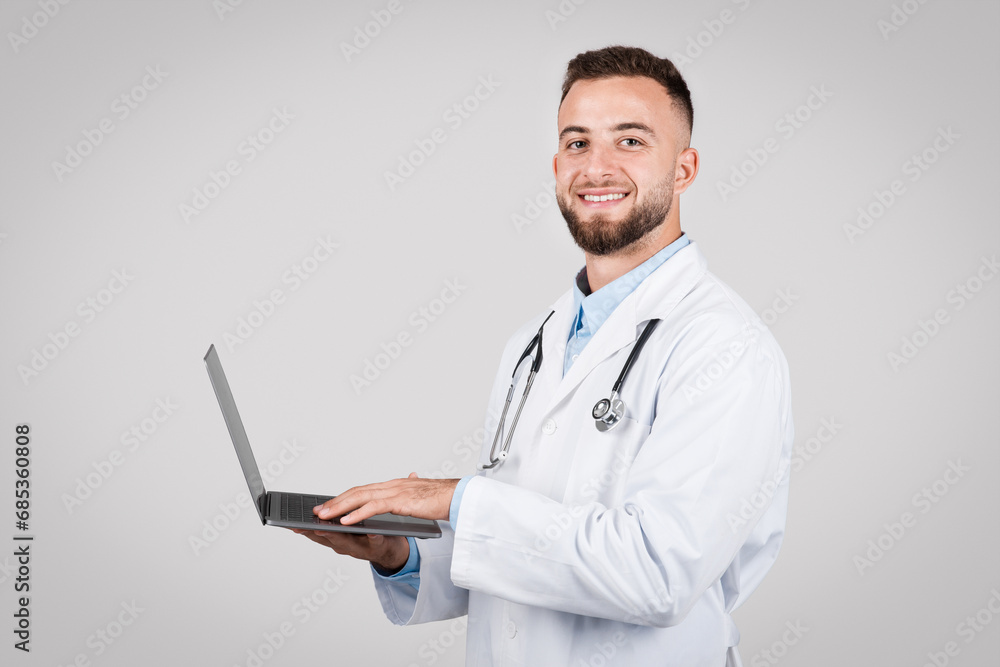 Male doctor using laptop with confident smile Male doctor using laptop with confident smile