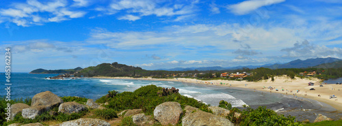 Panoramic view of Barra Garopaba beach, with rocks at the top of the viewpoint in the foreground.