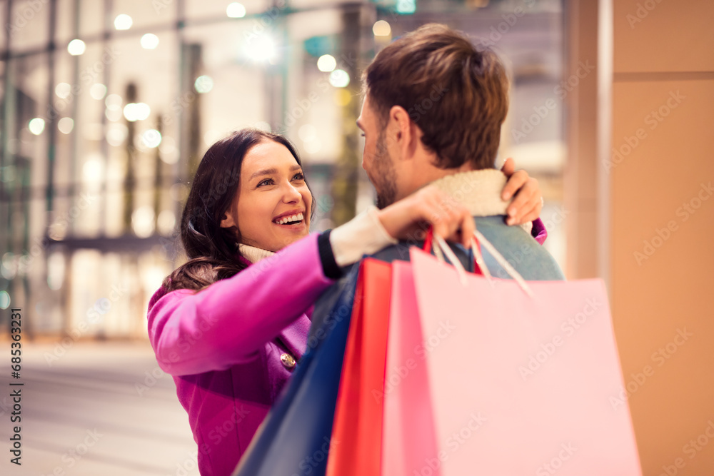 couple with Xmas shopping bags embracing outside of city mall couple with Xmas shopping bags embracing outside of city mall